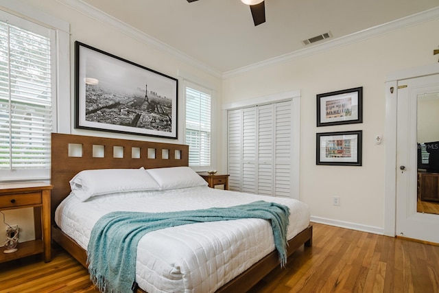 bedroom with crown molding, hardwood / wood-style floors, ceiling fan, and a closet