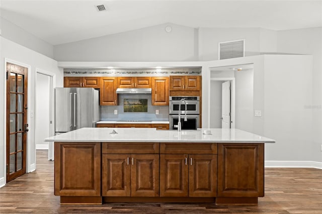 kitchen with lofted ceiling, backsplash, appliances with stainless steel finishes, and a center island with sink