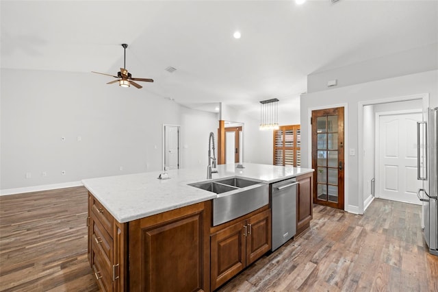 kitchen with stainless steel appliances, lofted ceiling, a kitchen island with sink, and sink