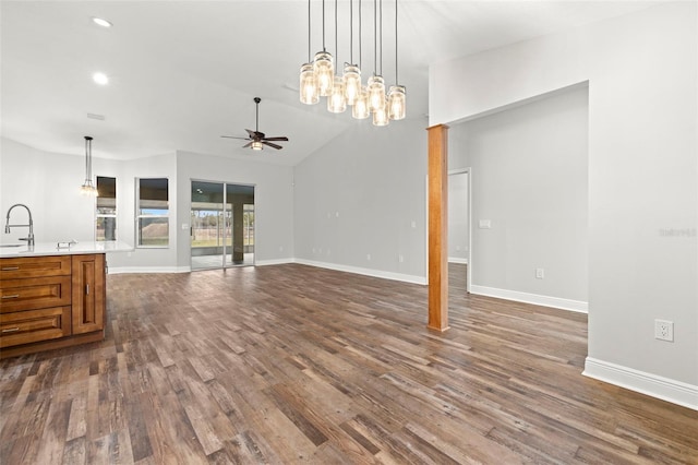 unfurnished living room with vaulted ceiling, dark hardwood / wood-style floors, sink, and ceiling fan