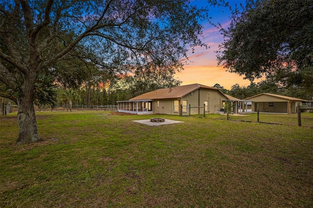 yard at dusk with a sunroom and an outdoor fire pit