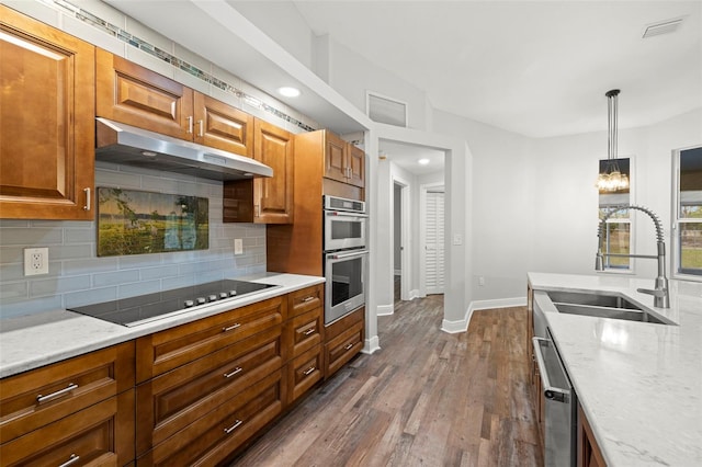 kitchen featuring sink, light stone counters, decorative light fixtures, appliances with stainless steel finishes, and decorative backsplash