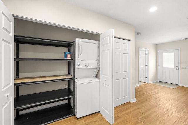 laundry room with light hardwood / wood-style floors and stacked washing maching and dryer