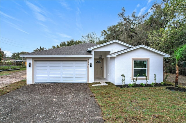 single story home featuring aphalt driveway, an attached garage, a shingled roof, stucco siding, and a front lawn