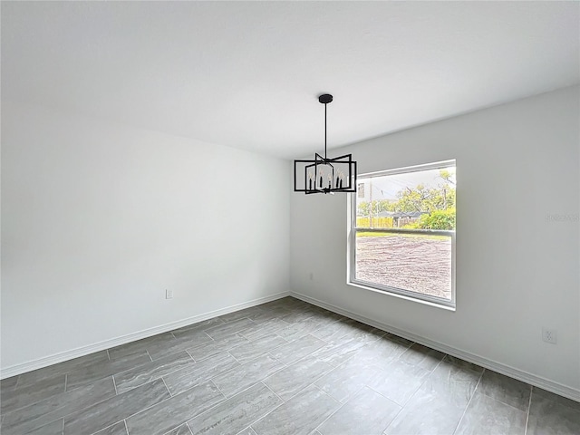 unfurnished dining area featuring a chandelier and baseboards