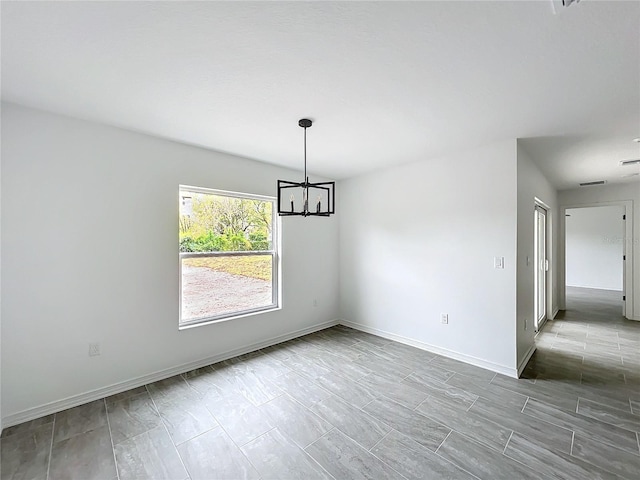 empty room featuring baseboards and a notable chandelier