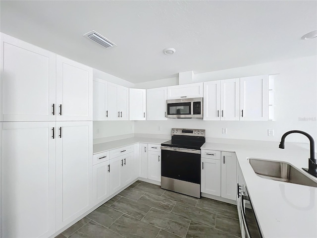 kitchen featuring stainless steel appliances, visible vents, a sink, and white cabinetry