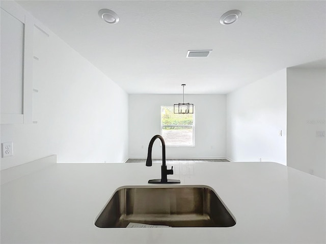 kitchen featuring light countertops, a sink, visible vents, and pendant lighting