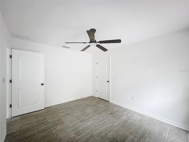 spare room with a ceiling fan, wood tiled floor, visible vents, and baseboards