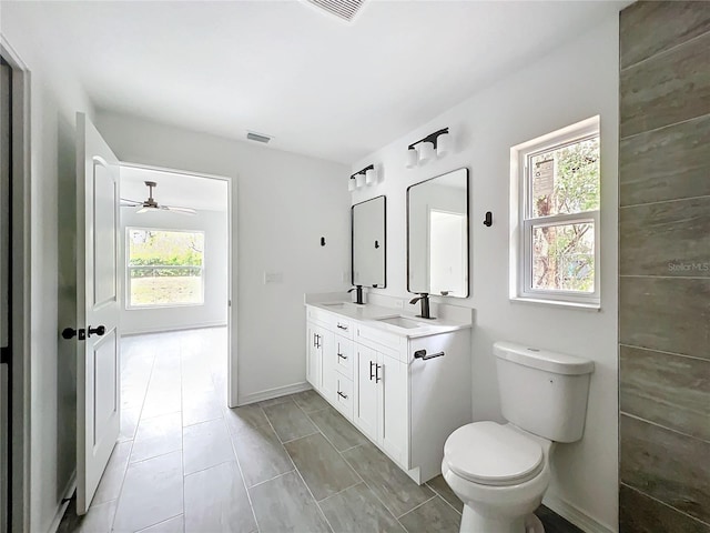 bathroom with visible vents, double vanity, a sink, and toilet