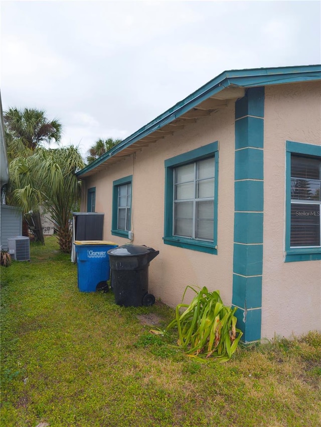 view of side of property featuring central AC and a yard