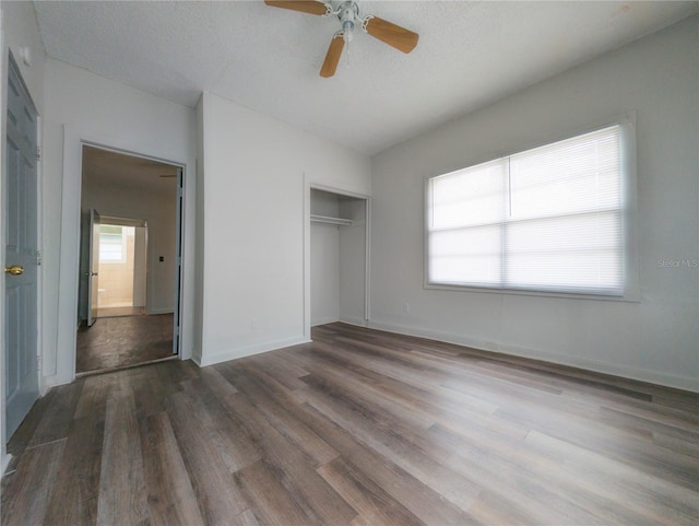 unfurnished bedroom featuring ceiling fan, a closet, dark hardwood / wood-style floors, and a textured ceiling