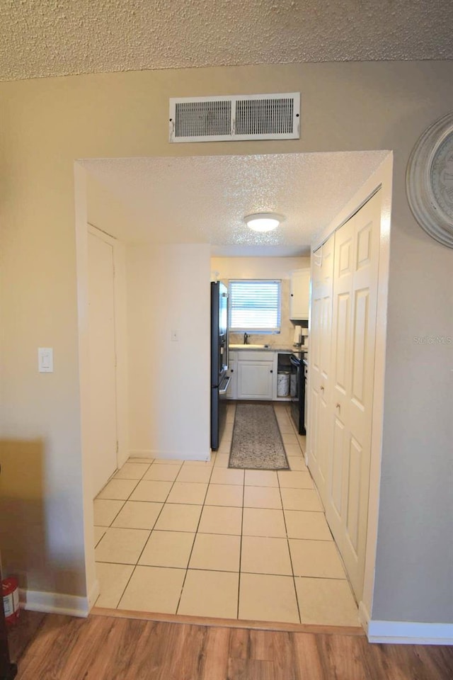 corridor featuring a textured ceiling and light tile patterned floors