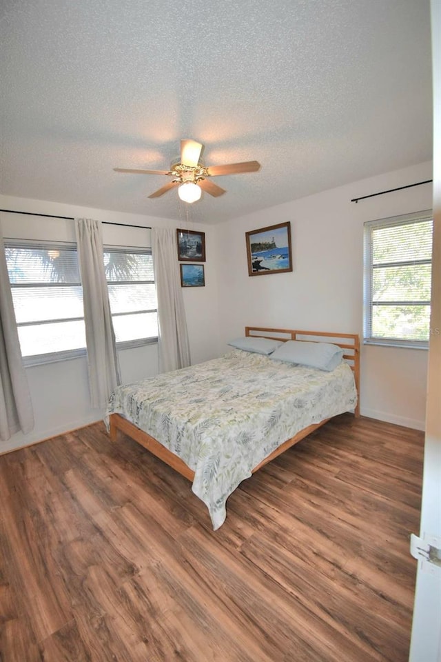 bedroom featuring ceiling fan, dark hardwood / wood-style floors, and a textured ceiling