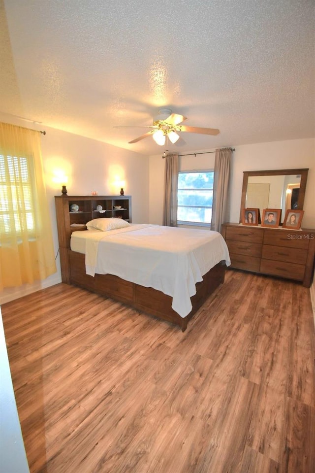 bedroom with ceiling fan, a textured ceiling, and hardwood / wood-style floors