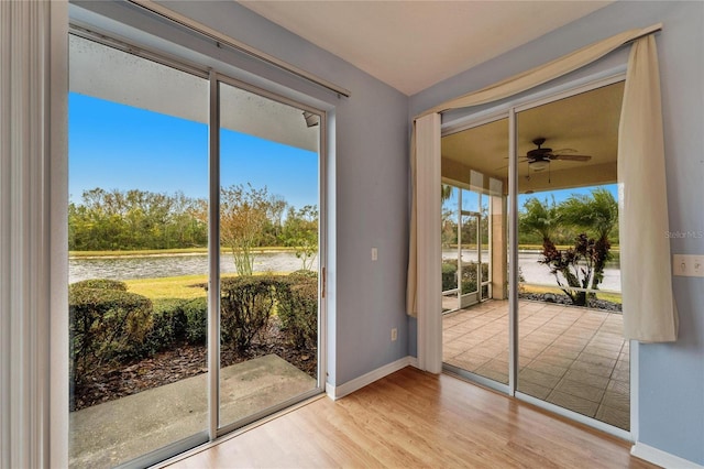 doorway to outside with a water view, ceiling fan, and light wood-type flooring