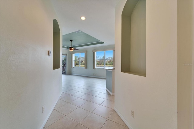 corridor with a raised ceiling and light tile patterned floors