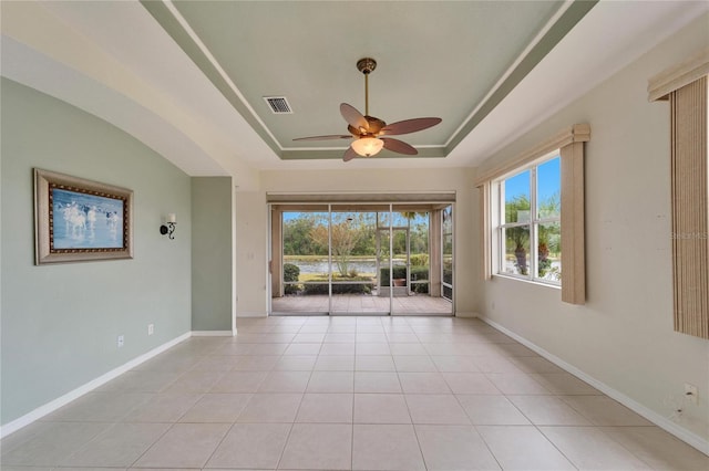 empty room featuring light tile patterned floors, a tray ceiling, and ceiling fan