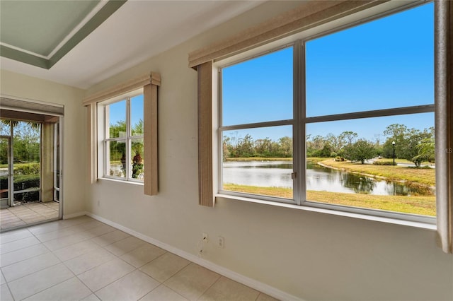 empty room featuring a water view, a healthy amount of sunlight, and light tile patterned floors