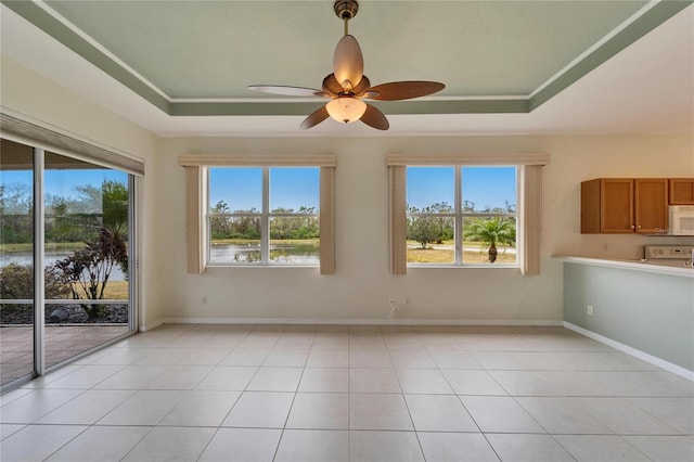 spare room featuring a water view, a raised ceiling, and light tile patterned flooring