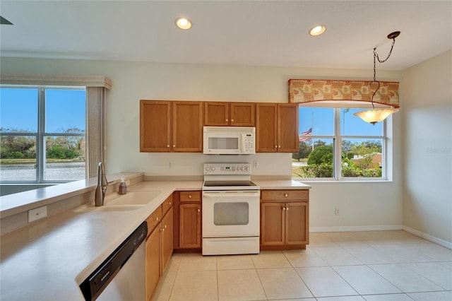 kitchen featuring hanging light fixtures, white appliances, sink, and light tile patterned flooring