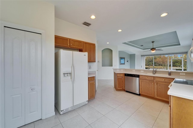 kitchen with light tile patterned floors, sink, white refrigerator with ice dispenser, stainless steel dishwasher, and a raised ceiling