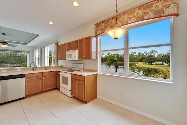 kitchen featuring sink, white appliances, ceiling fan, hanging light fixtures, and a water view