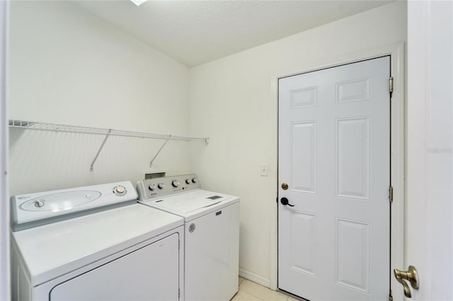 laundry room with light tile patterned flooring, washing machine and clothes dryer, and a textured ceiling