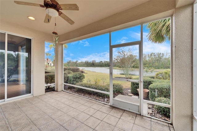 unfurnished sunroom with a water view and ceiling fan