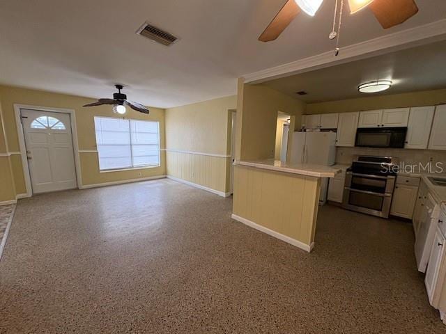 kitchen featuring double oven range, ceiling fan, white refrigerator, and white cabinets