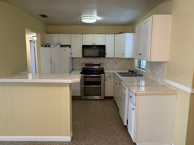 kitchen with kitchen peninsula, tile counters, white appliances, white cabinets, and sink