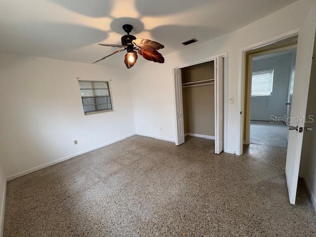 unfurnished bedroom with ceiling fan and a closet