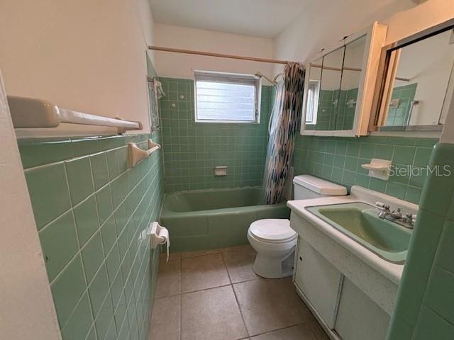 full bathroom with toilet, tile walls, tile patterned flooring, sink, and shower / bath combo with shower curtain