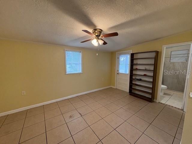 unfurnished bedroom featuring ceiling fan, a textured ceiling, connected bathroom, and light tile patterned flooring