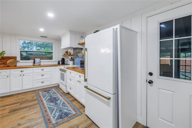 kitchen featuring white cabinetry, butcher block counters, light hardwood / wood-style flooring, and white appliances