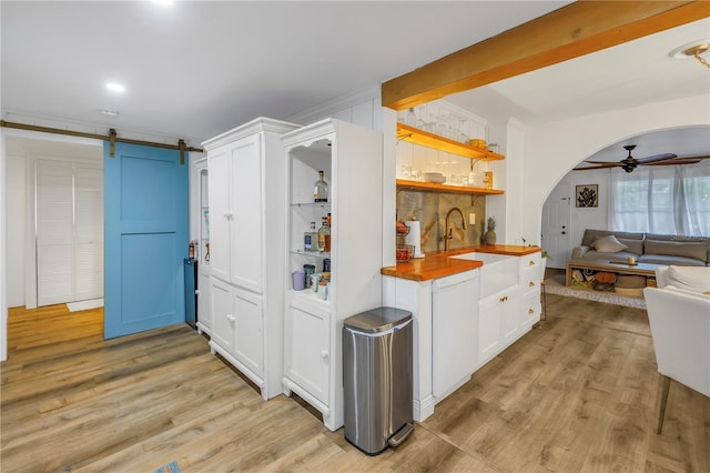 kitchen featuring ceiling fan, a barn door, light hardwood / wood-style floors, white cabinets, and wood counters