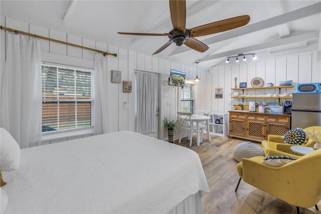 bedroom featuring ceiling fan, light wood-type flooring, stainless steel fridge, and multiple windows