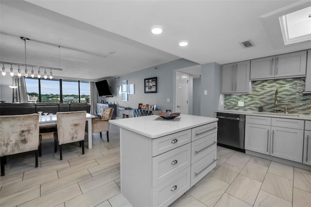 kitchen featuring dishwashing machine, a center island, backsplash, hanging light fixtures, and sink