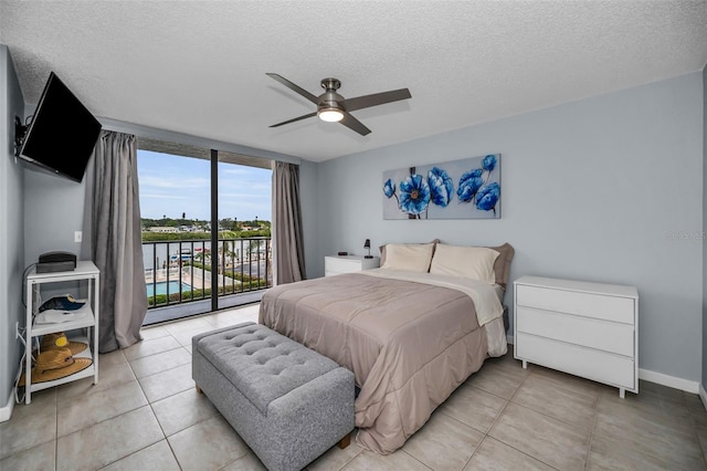 tiled bedroom featuring a textured ceiling, ceiling fan, expansive windows, and access to outside