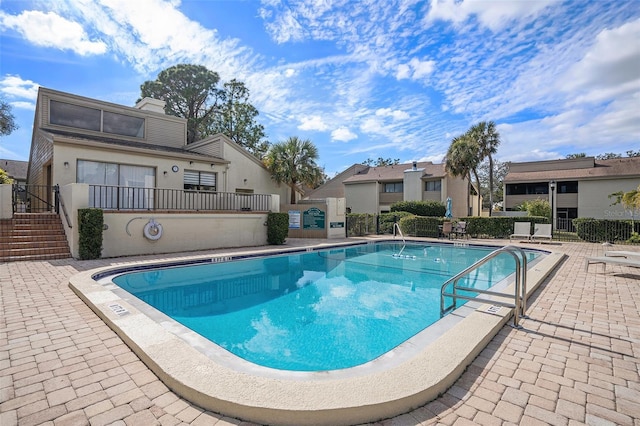 community pool with a patio area and fence