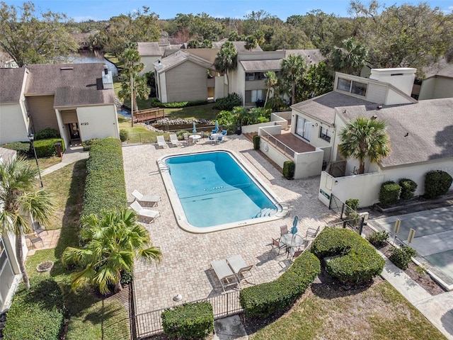 community pool with a residential view, fence, and a patio