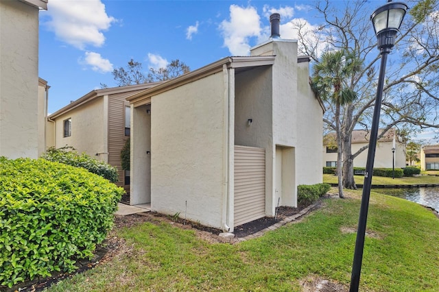 view of home's exterior with a water view, a yard, and stucco siding