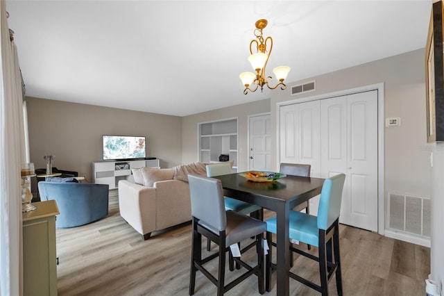 dining space with an inviting chandelier, visible vents, and wood finished floors