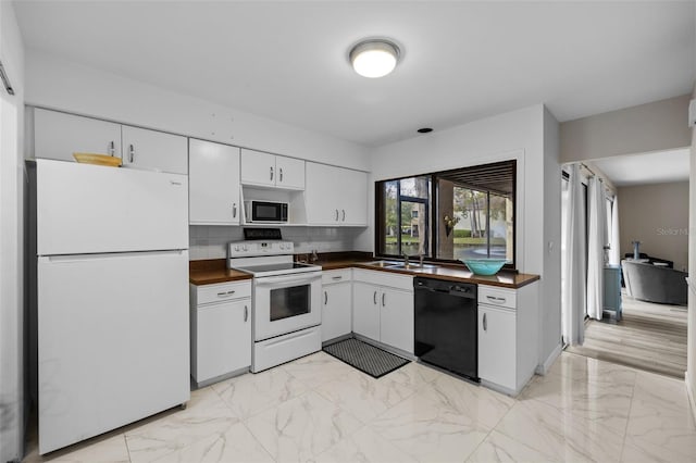 kitchen with marble finish floor, white appliances, a sink, and white cabinets