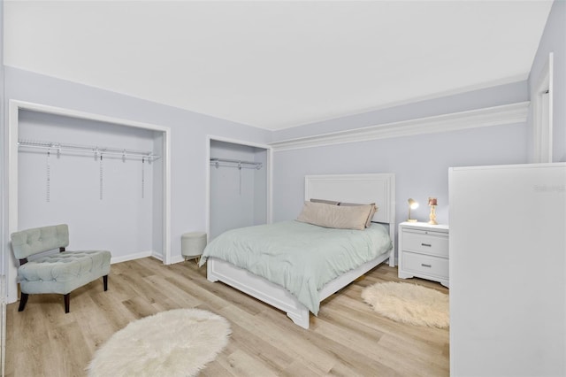 bedroom with baseboards, wood finished floors, and multiple closets