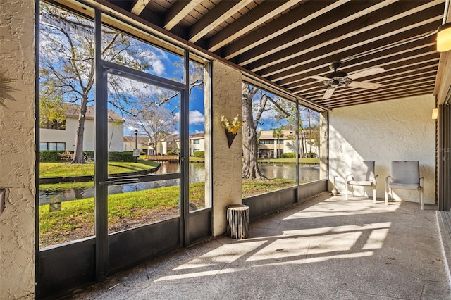 unfurnished sunroom with a residential view, a water view, and ceiling fan