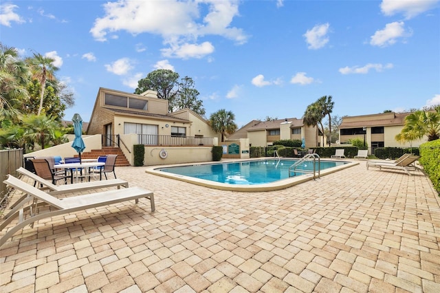 community pool with fence and a patio