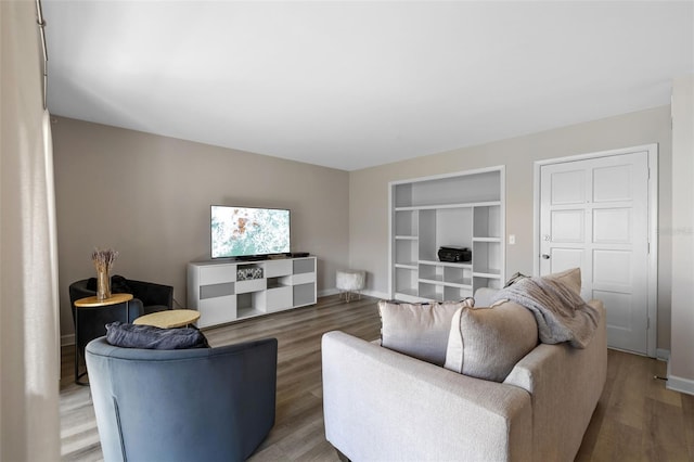 living room with built in features, baseboards, and wood finished floors