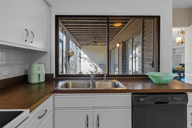 kitchen with dishwasher, dark countertops, a sink, and white cabinetry