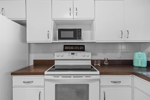 kitchen with tasteful backsplash, dark countertops, white cabinets, and white electric range